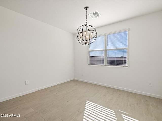 spare room with a chandelier and light hardwood / wood-style floors