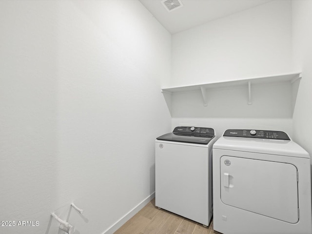 clothes washing area with light hardwood / wood-style floors and washing machine and clothes dryer