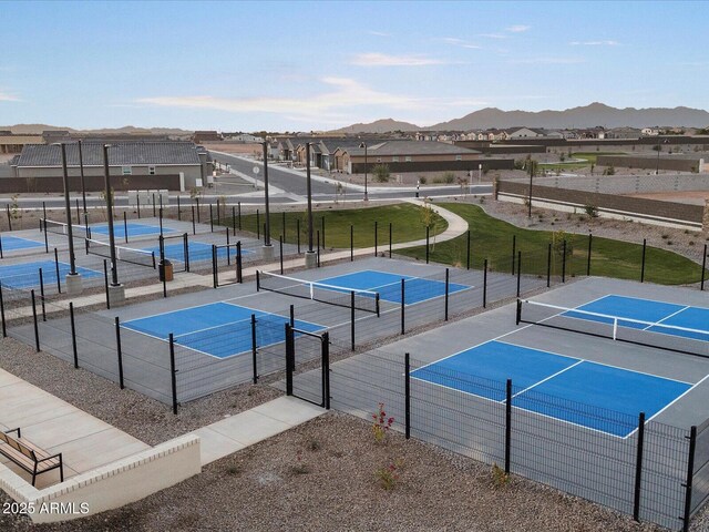 view of sport court with basketball hoop, a yard, and a mountain view