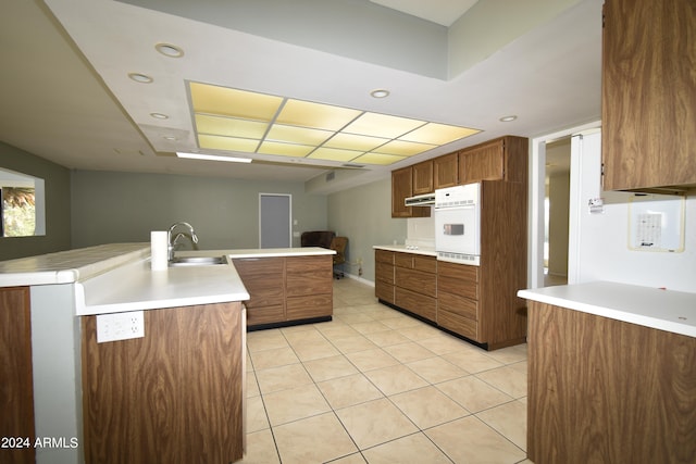 kitchen featuring oven, sink, light tile patterned floors, and kitchen peninsula