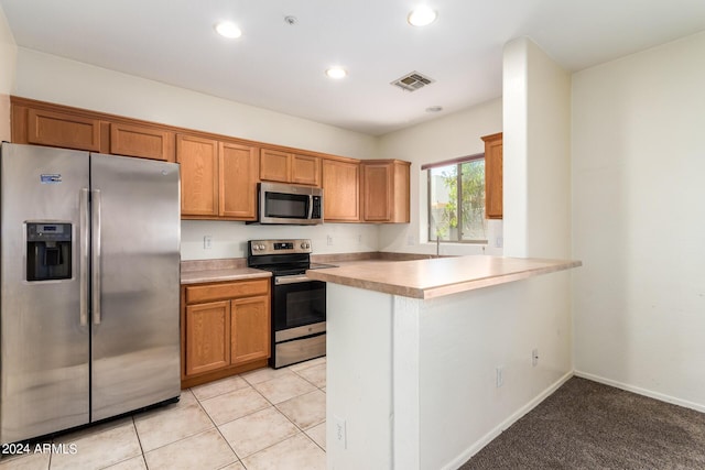 kitchen featuring light tile patterned floors, kitchen peninsula, and appliances with stainless steel finishes