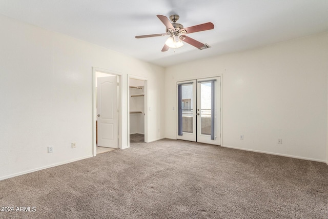 unfurnished bedroom with ceiling fan, a walk in closet, access to exterior, and light colored carpet