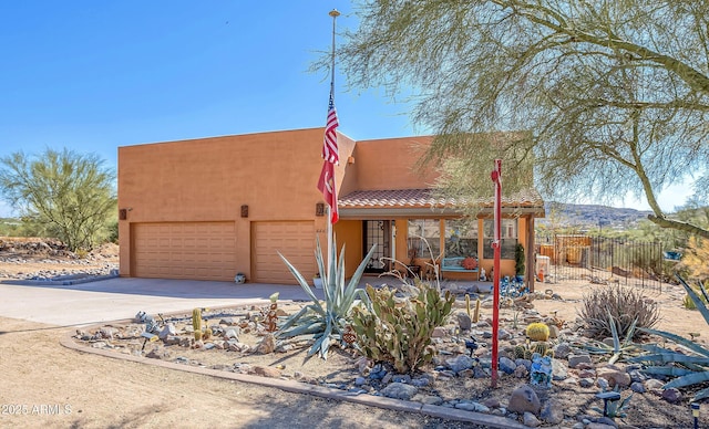 44421 N 12th St, New River, AZ 85087 - pueblo revival-style home featuring concrete driveway, stucco siding, a porch, a tile roof, and an attached garage