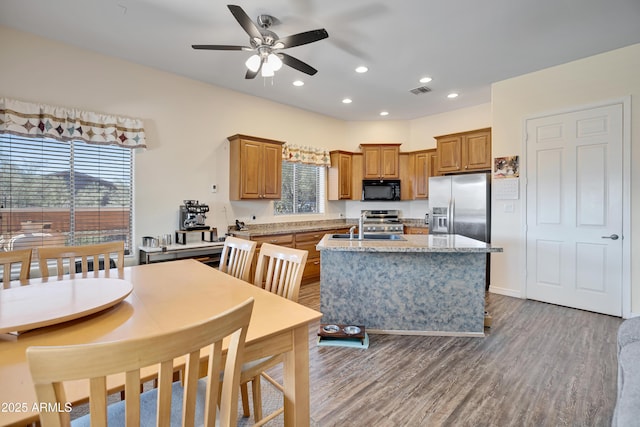 44421 N 12th St, New River, AZ 85087 - kitchen featuring stainless steel appliances, ceiling fan, an island with sink, wood finished floors, and brown cabinetry