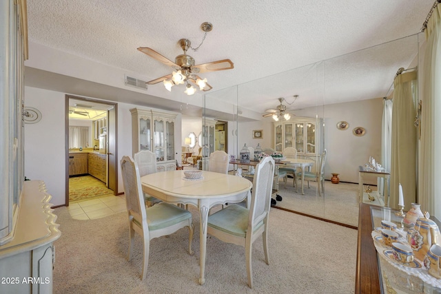 carpeted dining space with ceiling fan, french doors, and a textured ceiling