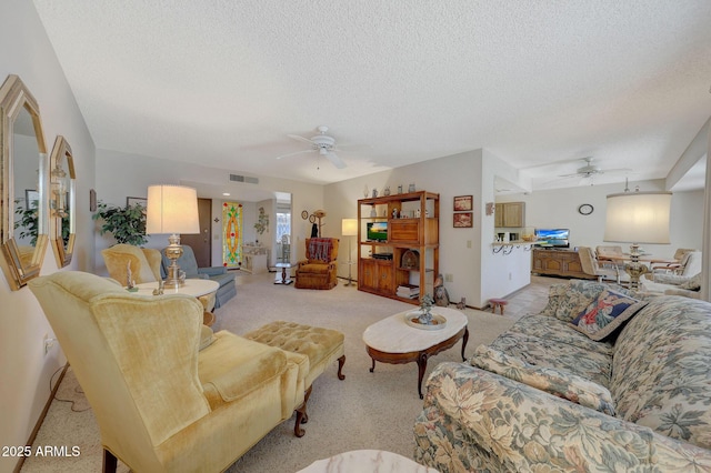 living room featuring ceiling fan, light carpet, and a textured ceiling