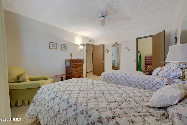 bedroom featuring ceiling fan, light colored carpet, and a textured ceiling