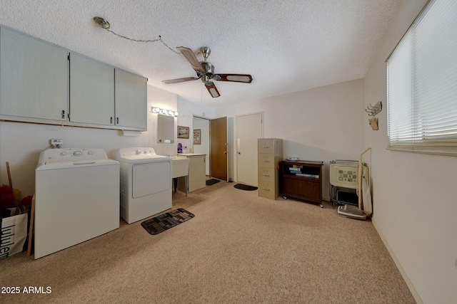 laundry room with ceiling fan, cabinets, a textured ceiling, separate washer and dryer, and light carpet