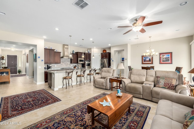 living room with light tile patterned floors, sink, and ceiling fan with notable chandelier