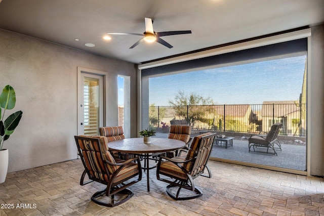 dining room featuring stone tile flooring, a wealth of natural light, and a ceiling fan