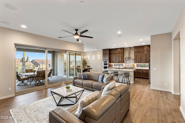 living area with light wood finished floors, baseboards, recessed lighting, and a ceiling fan