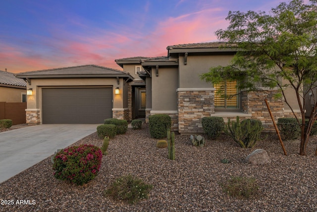 prairie-style home featuring an attached garage, concrete driveway, stucco siding, and stone siding