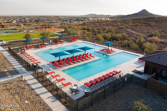 community pool featuring a mountain view, a patio, and fence