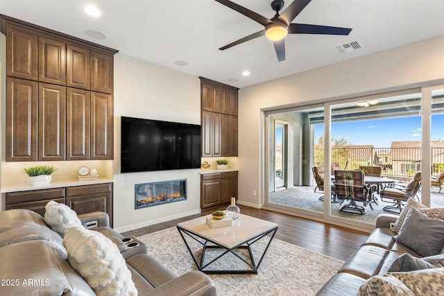 living area featuring a ceiling fan, visible vents, recessed lighting, dark wood-style flooring, and baseboards