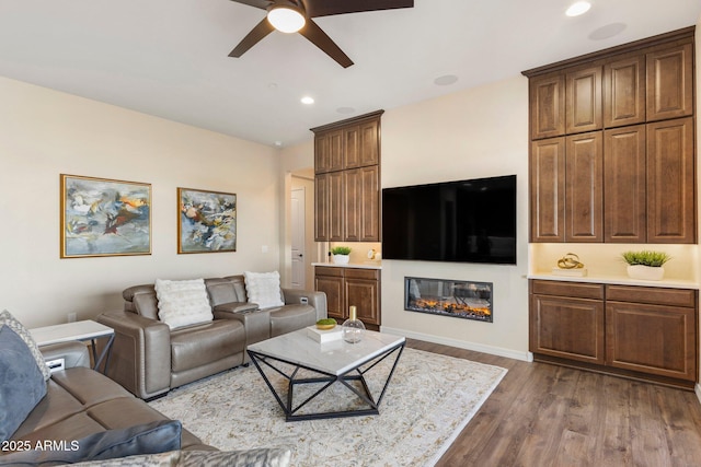 living area featuring recessed lighting, dark wood finished floors, baseboards, and ceiling fan