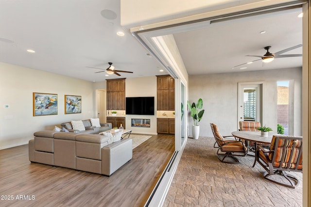 living area with a large fireplace, a ceiling fan, and recessed lighting