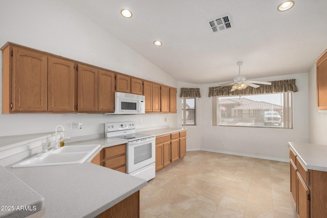 kitchen with white appliances, visible vents, vaulted ceiling, light countertops, and a sink