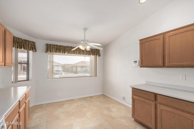 unfurnished dining area with plenty of natural light, a ceiling fan, and baseboards