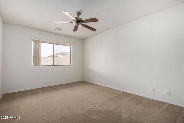 spare room with carpet, visible vents, baseboards, and ceiling fan