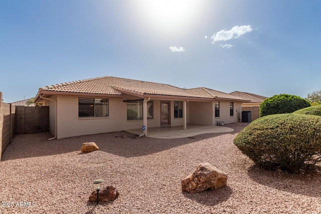 rear view of house with a tile roof, fence, central AC, and a patio