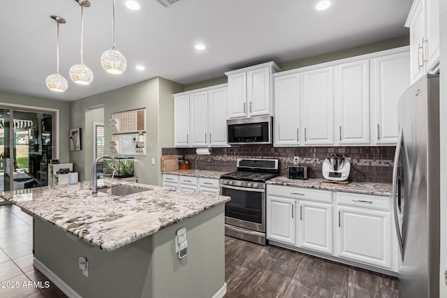 kitchen featuring sink, white cabinetry, hanging light fixtures, a center island with sink, and appliances with stainless steel finishes