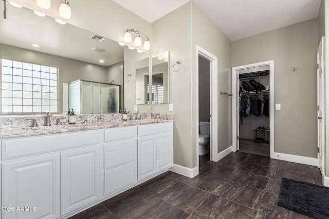 bathroom featuring vanity, a shower with shower door, and toilet