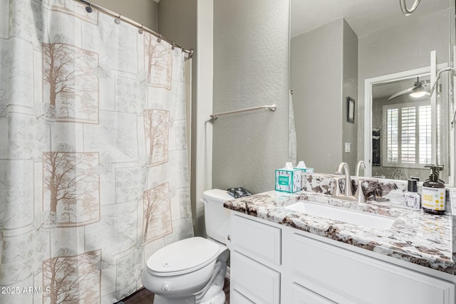 bathroom with walk in shower, ceiling fan, vanity, and toilet