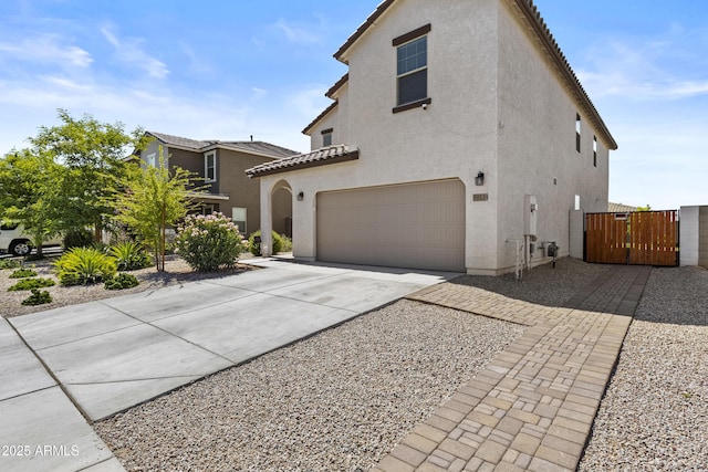 19239 W Elm St, Litchfield Park, AZ 85340 - view of property exterior featuring a garage, stucco siding, concrete driveway, and a gate