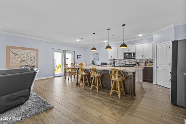 19239 W Elm St, Litchfield Park, AZ 85340 - kitchen featuring appliances with stainless steel finishes, a kitchen bar, open floor plan, light wood-style floors, and white cabinets
