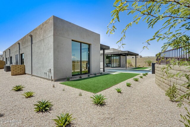 rear view of property featuring a pool and cooling unit