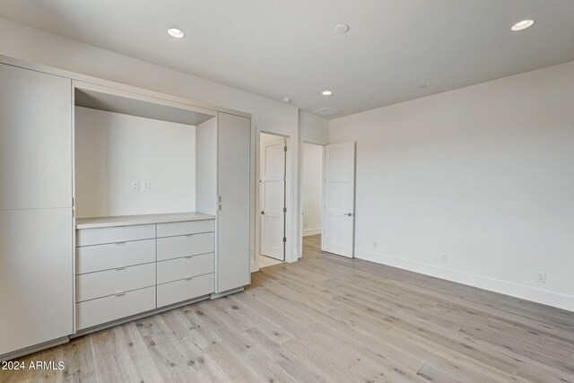 unfurnished bedroom featuring light wood-type flooring and a closet