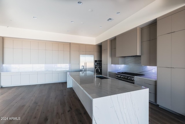 kitchen featuring tasteful backsplash, stainless steel appliances, sink, dark hardwood / wood-style flooring, and a spacious island