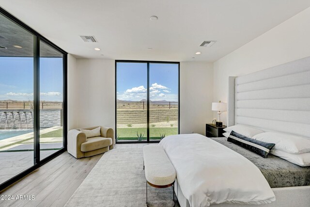 bedroom with access to exterior, light wood-type flooring, and floor to ceiling windows