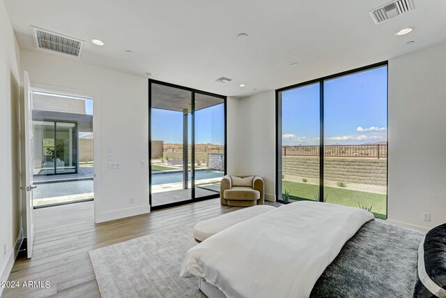 bedroom featuring a wall of windows, light hardwood / wood-style floors, multiple windows, and access to exterior