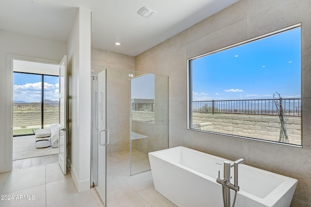 bathroom with tile patterned flooring, tile walls, and plenty of natural light