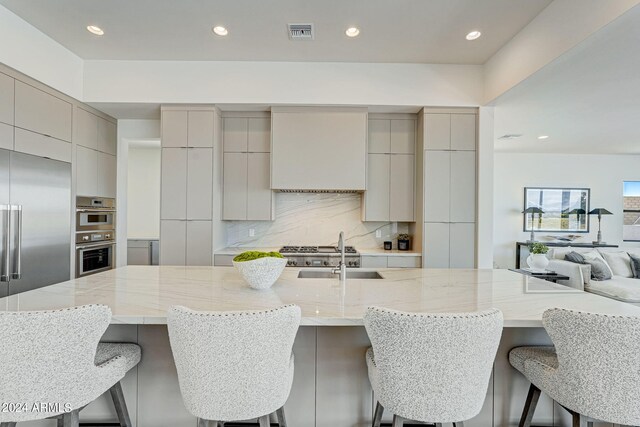 kitchen with a breakfast bar area, appliances with stainless steel finishes, a large island, and tasteful backsplash