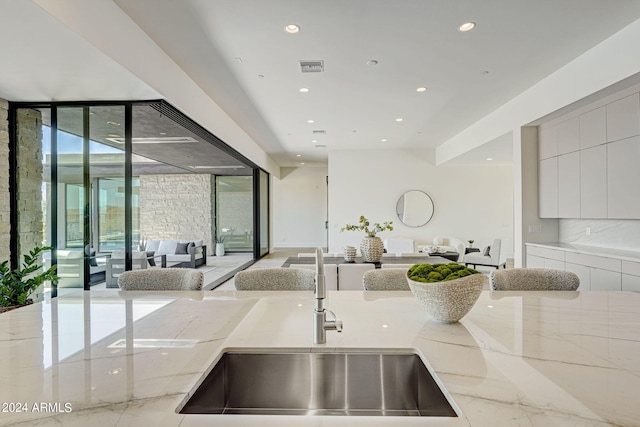 kitchen with sink, a wall of windows, and light stone countertops