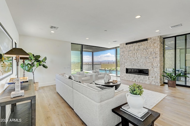 living room featuring a fireplace, light hardwood / wood-style floors, and expansive windows