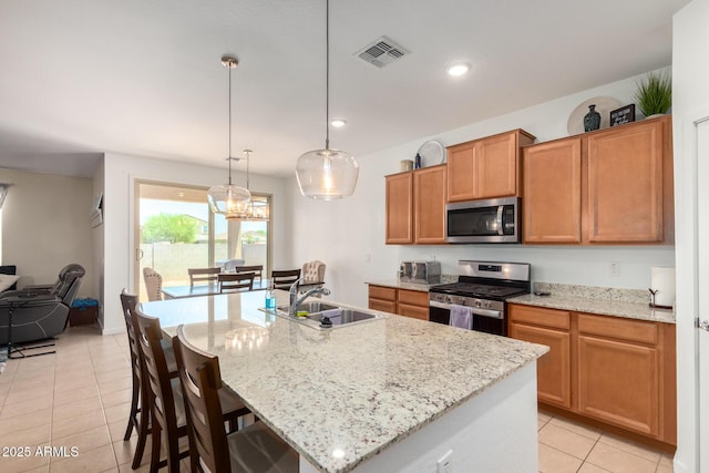 kitchen featuring sink, stainless steel appliances, and an island with sink