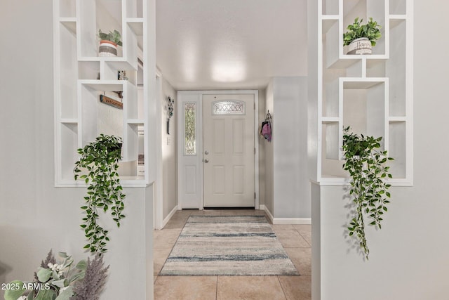 foyer entrance with light tile patterned floors and baseboards