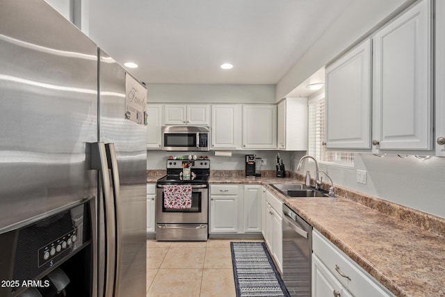 kitchen featuring white cabinetry, light tile patterned floors, appliances with stainless steel finishes, and a sink