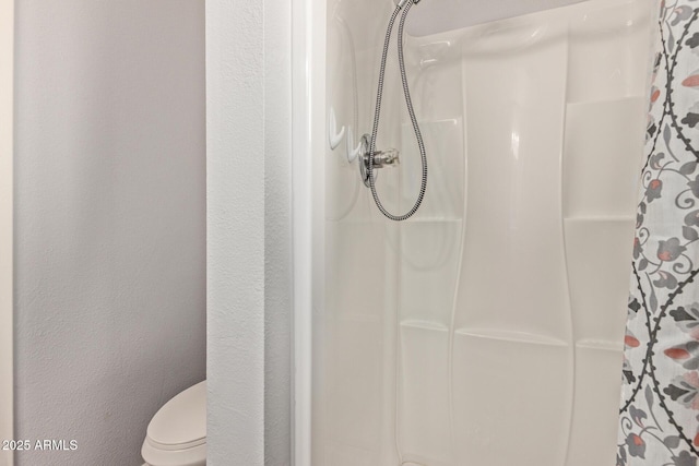 bathroom featuring toilet, a shower with shower curtain, and a textured wall