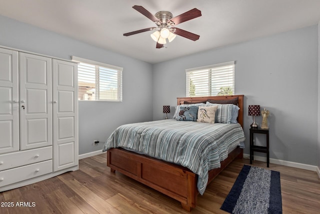 bedroom with multiple windows, baseboards, and wood finished floors