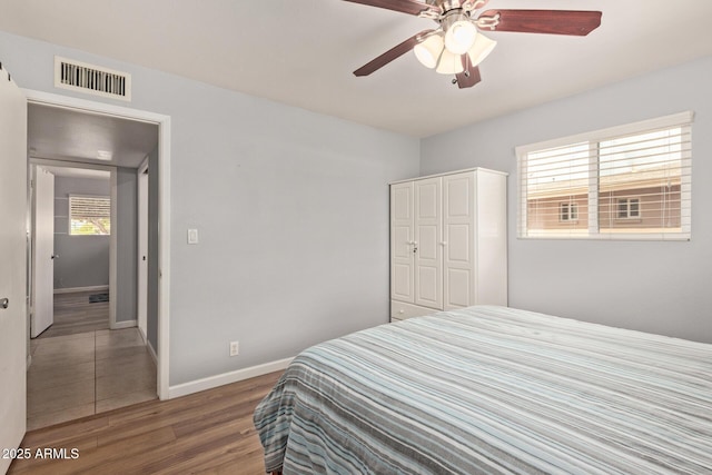 bedroom featuring visible vents, baseboards, wood finished floors, a closet, and a ceiling fan