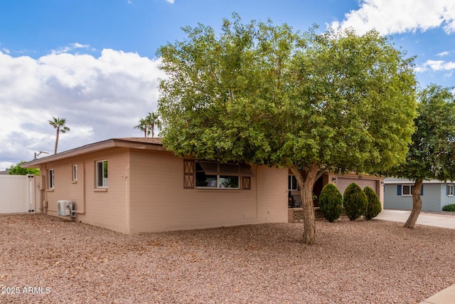 view of front facade featuring cooling unit, an attached garage, concrete driveway, and fence