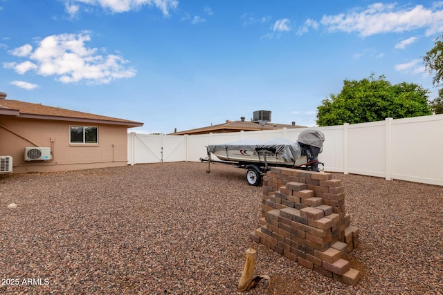 view of yard with ac unit, a gate, a fenced backyard, and cooling unit