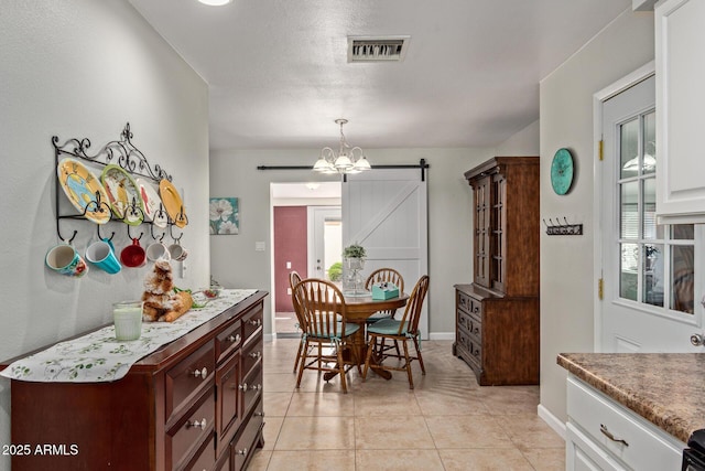 dining area featuring light tile patterned floors, a barn door, baseboards, and visible vents