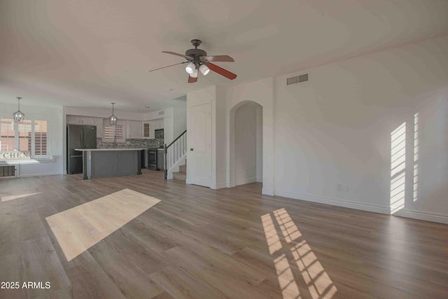20722 N 38th St, Phoenix, AZ 85050 - unfurnished living room with a ceiling fan, wood finished floors, arched walkways, and stairway
