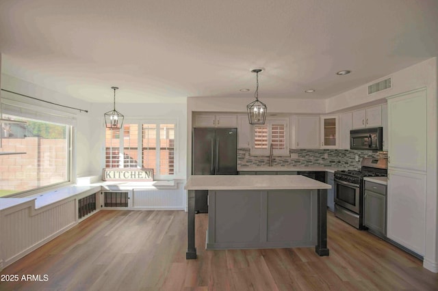 20722 N 38th St, Phoenix, AZ 85050 - kitchen featuring stainless steel appliances, light countertops, light wood-style floors, backsplash, and glass insert cabinets