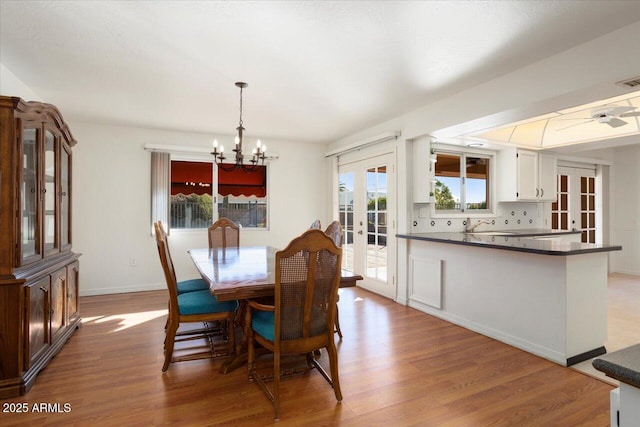 dining area with french doors, a chandelier, and light wood-type flooring